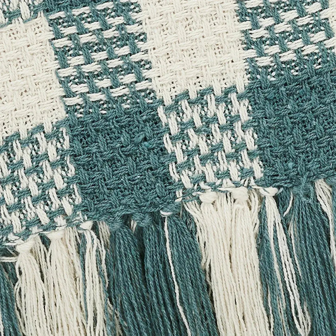 Close-up of a woven fabric with blue and white colors and tassels.