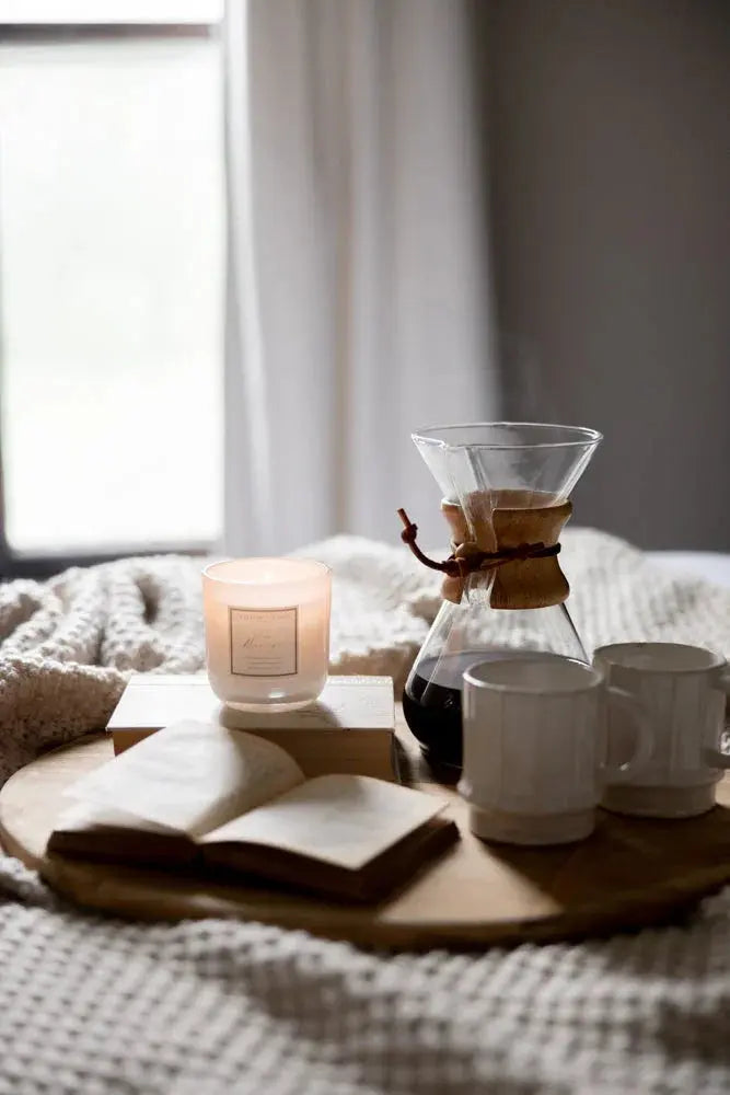 Cozy farmhouse coffee setup with candle, book, and Chemex on wooden tray by window