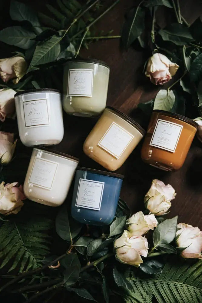 Farmhouse-style scented candles in glass jars with dried roses and ferns, cozy home decor