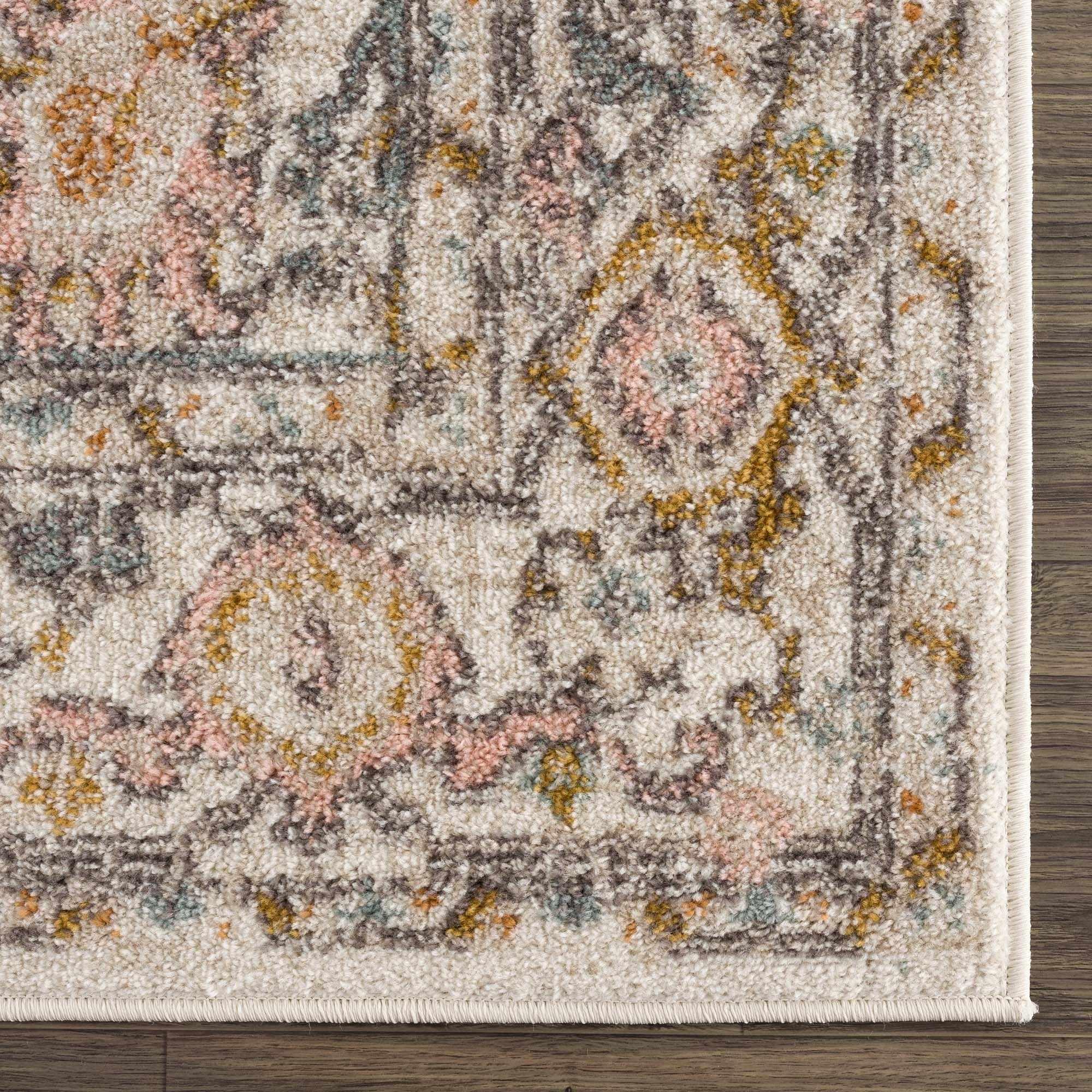 Cozy farmhouse-style area rug with vintage floral pattern, soft pastel colors, and fringe border on wood floor