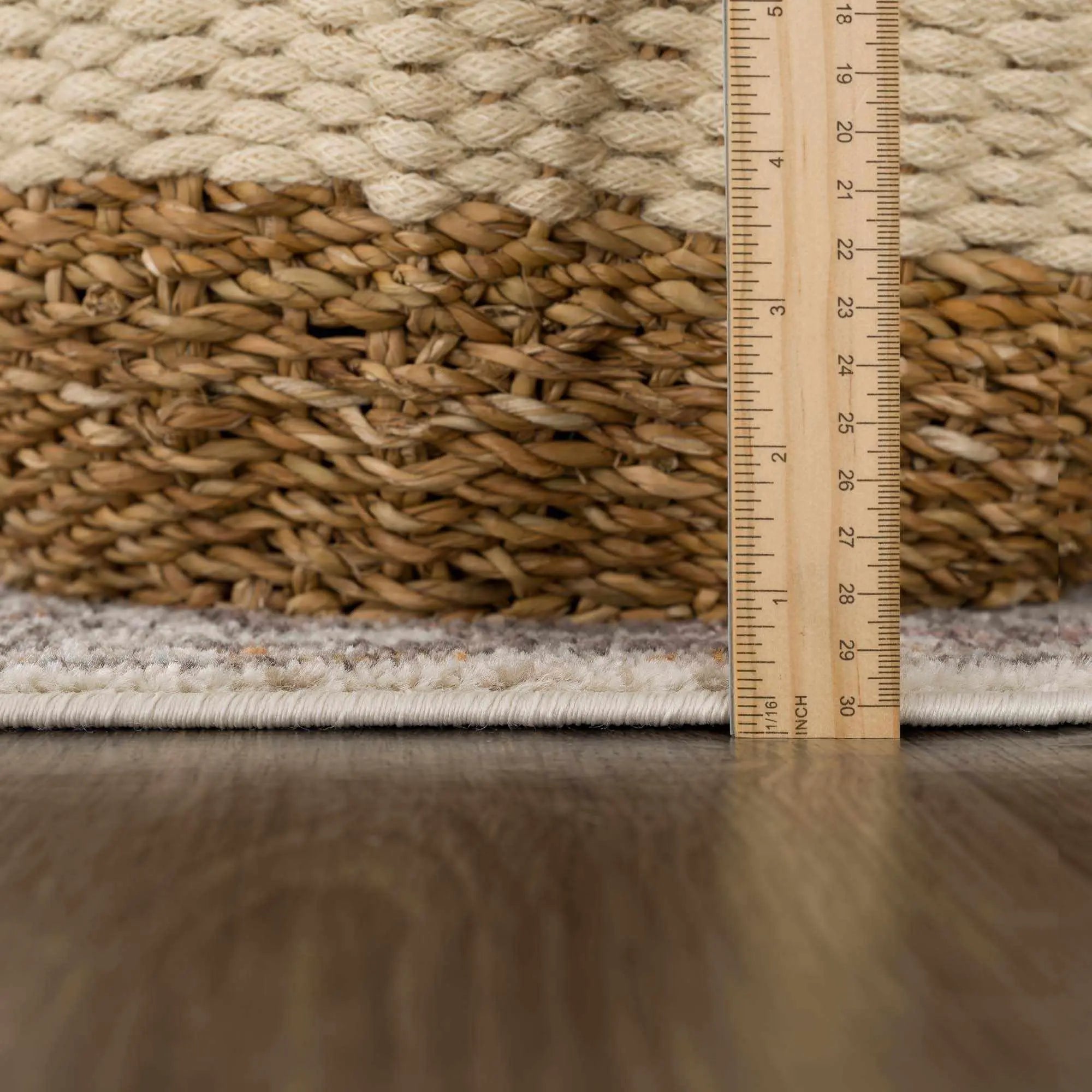 Woven jute rug with natural texture, measured with wooden ruler on hardwood floor