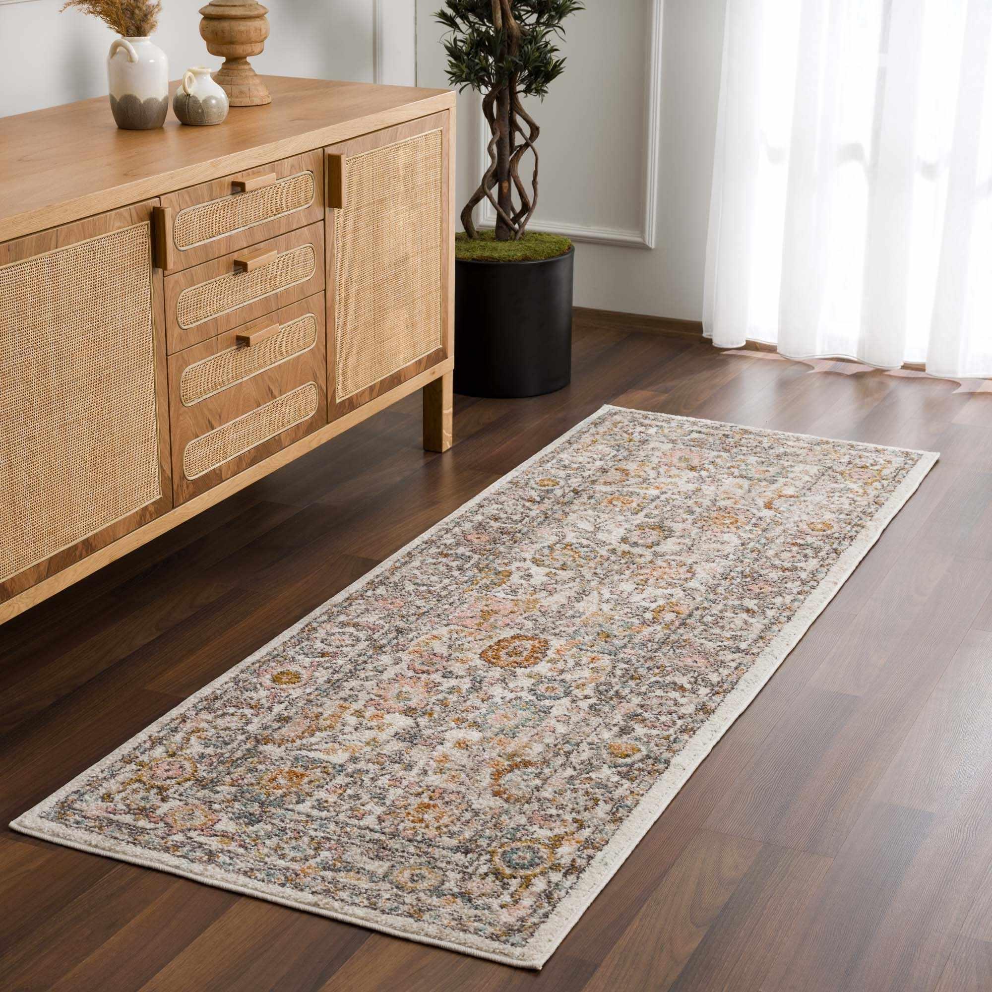 Vintage-style runner rug with floral pattern, perfect for farmhouse or cottage decor, placed on hardwood floor beside wooden sideboard.