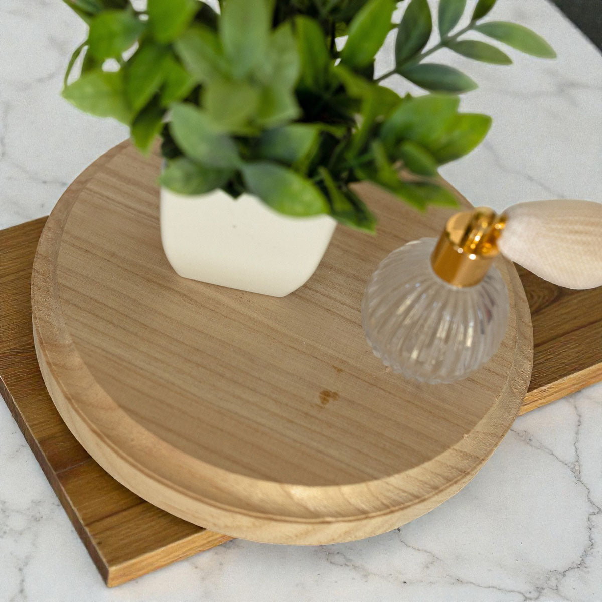Wooden tray with a plant and decorative item on a marble surface
