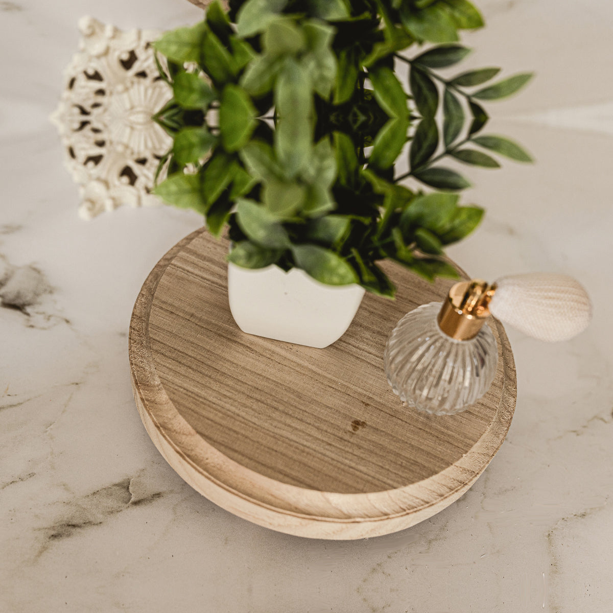 Decorative tray with a plant, decorative item, and small lamp on a marble surface