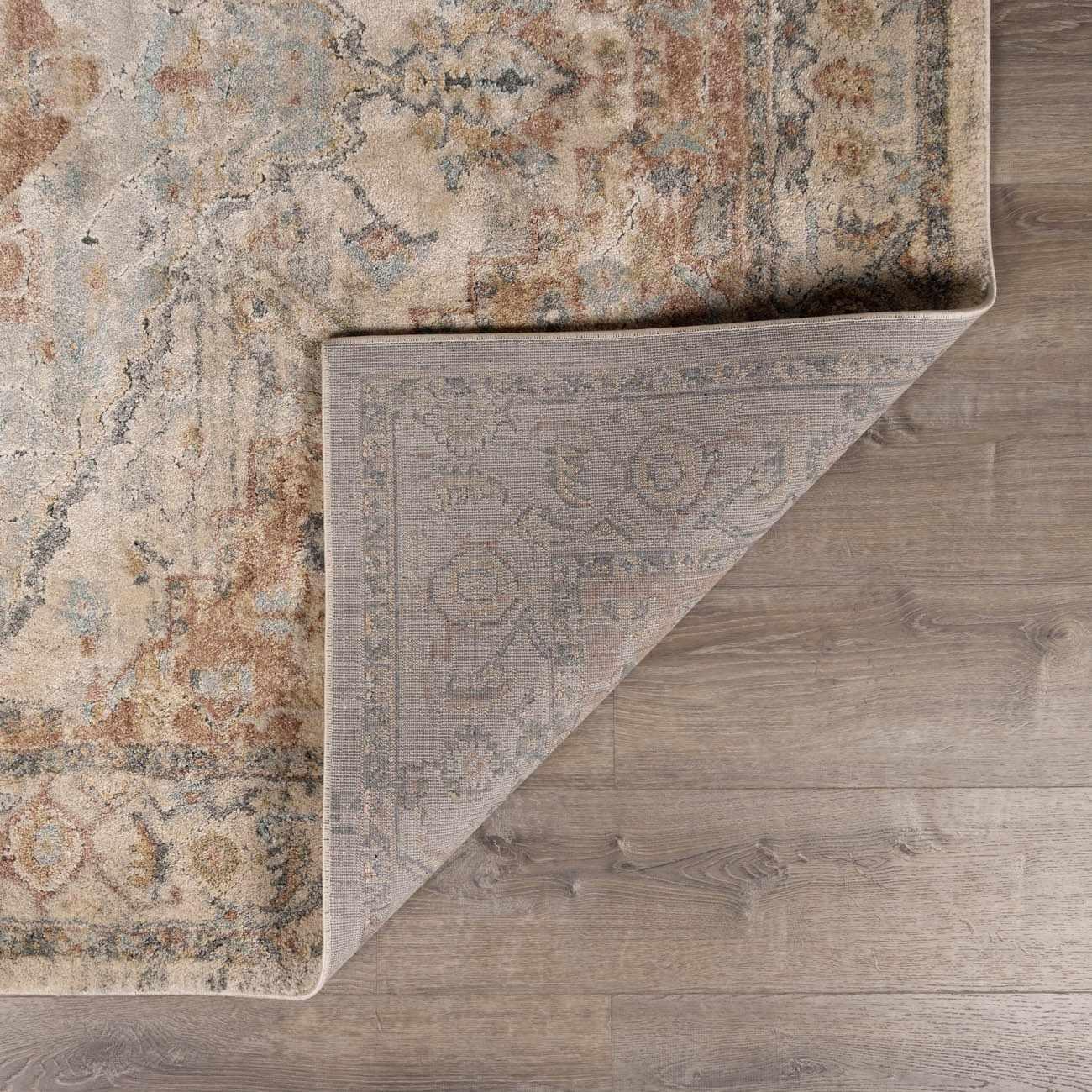 Vintage-style area rug with muted floral pattern on wood floor, cozy farmhouse decor