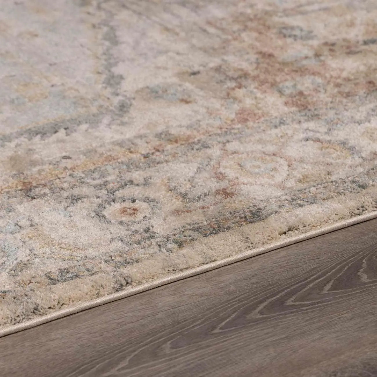 Vintage-style area rug with soft beige, blue, and gray tones on wood floor, perfect for cozy farmhouse decor