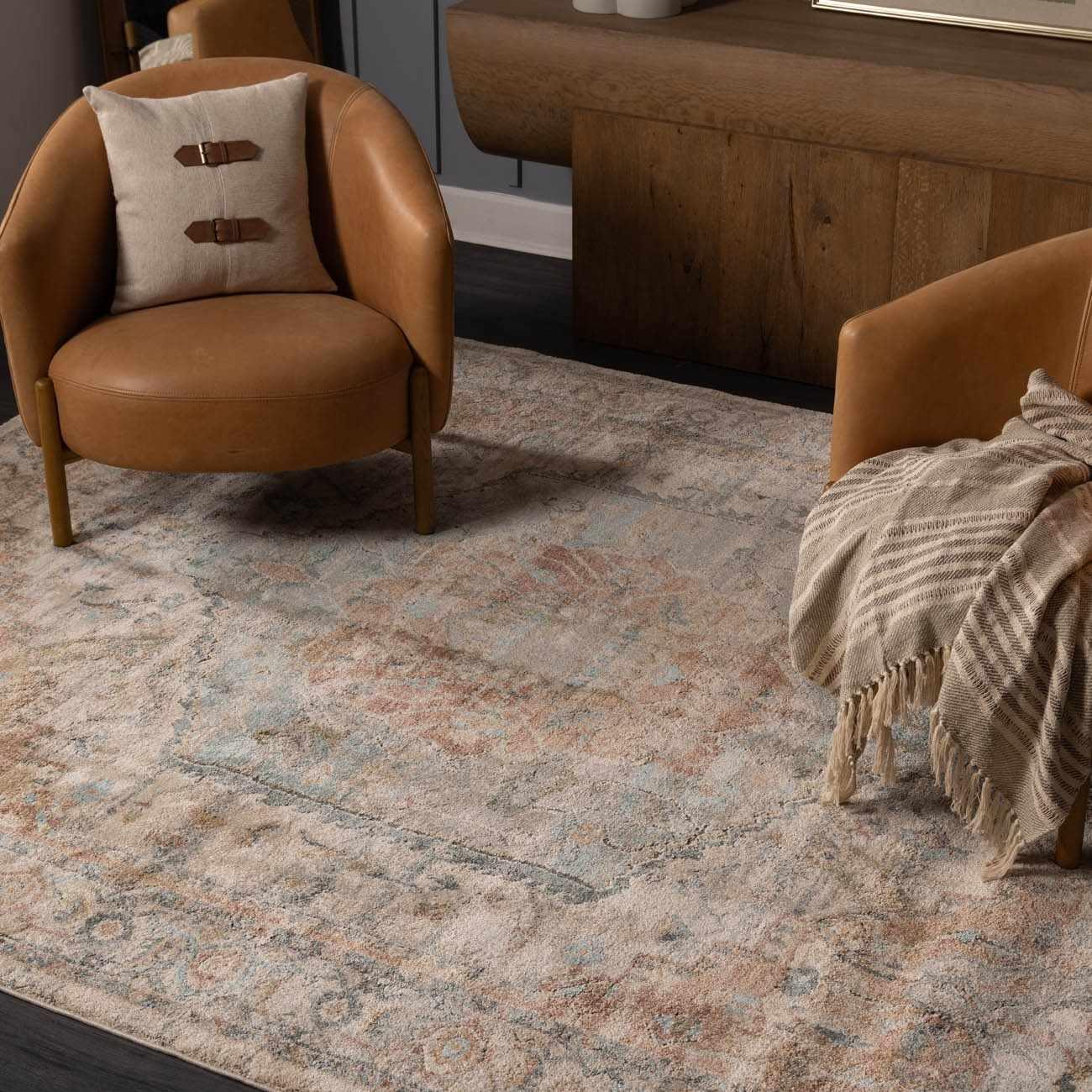 Cozy farmhouse living room with vintage area rug, leather armchairs, and throw blanket for warm home decor