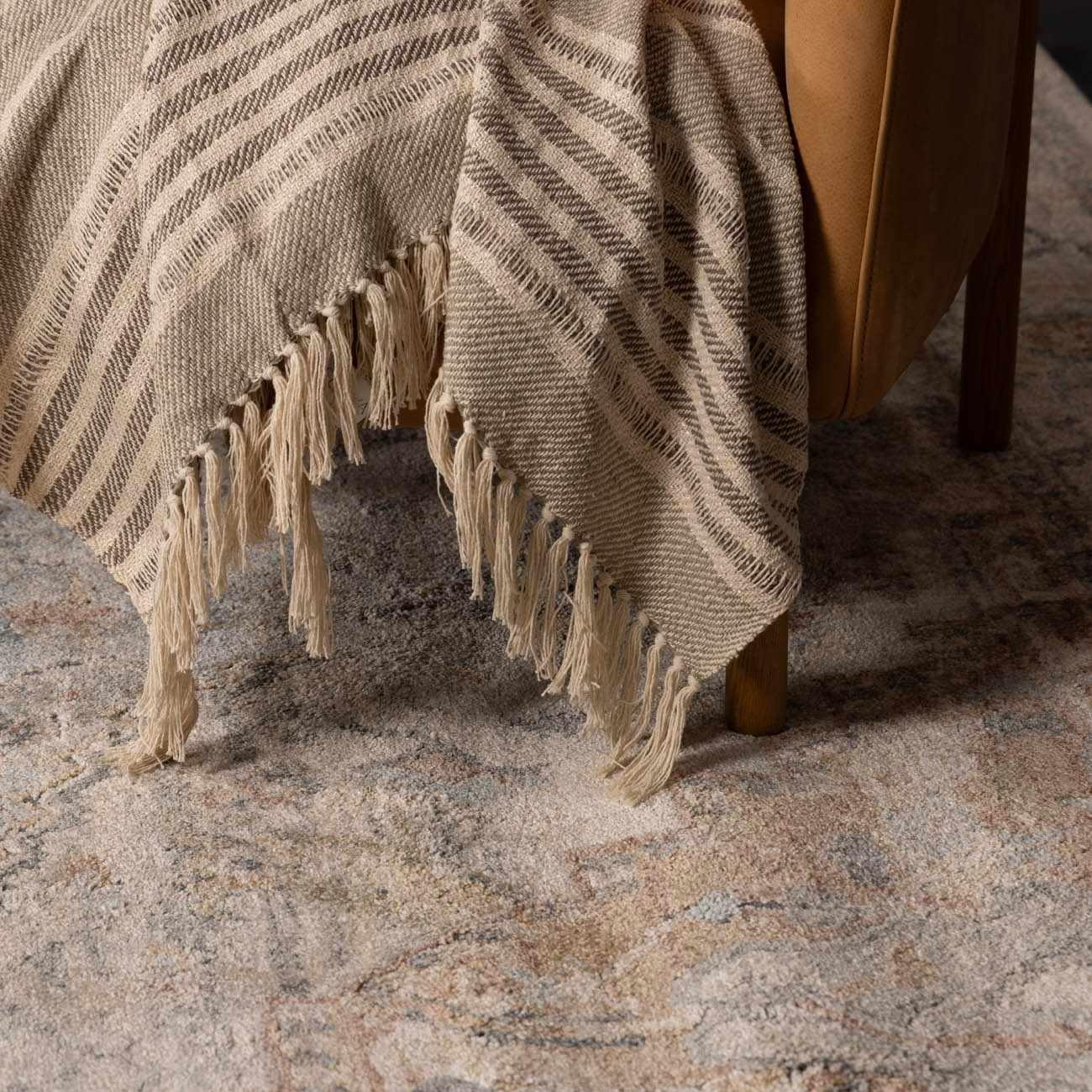 Cozy striped throw blanket with fringe draped over armchair, perfect for farmhouse or cottage decor