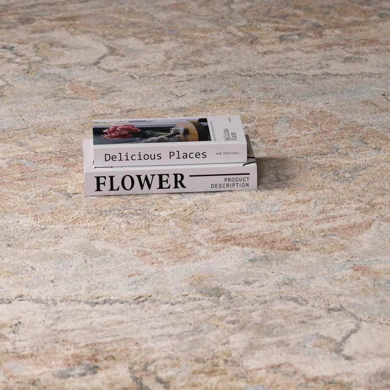 Stacked books 'Delicious Places' and 'FLOWER' on cozy patterned rug, farmhouse decor style