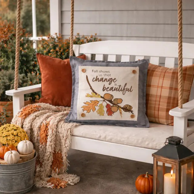 Decorative pillow with autumn design on a swing with pumpkins and lanterns.