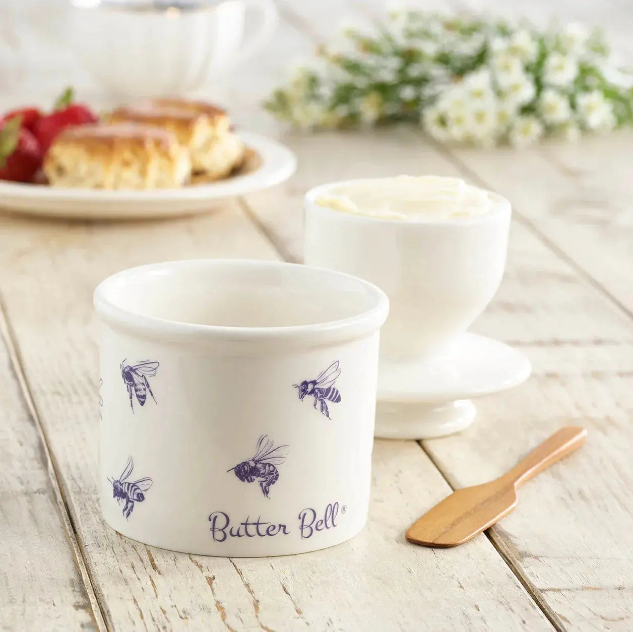 White ceramic butter bell with purple bee design, farmhouse kitchen decor, rustic wooden table setting