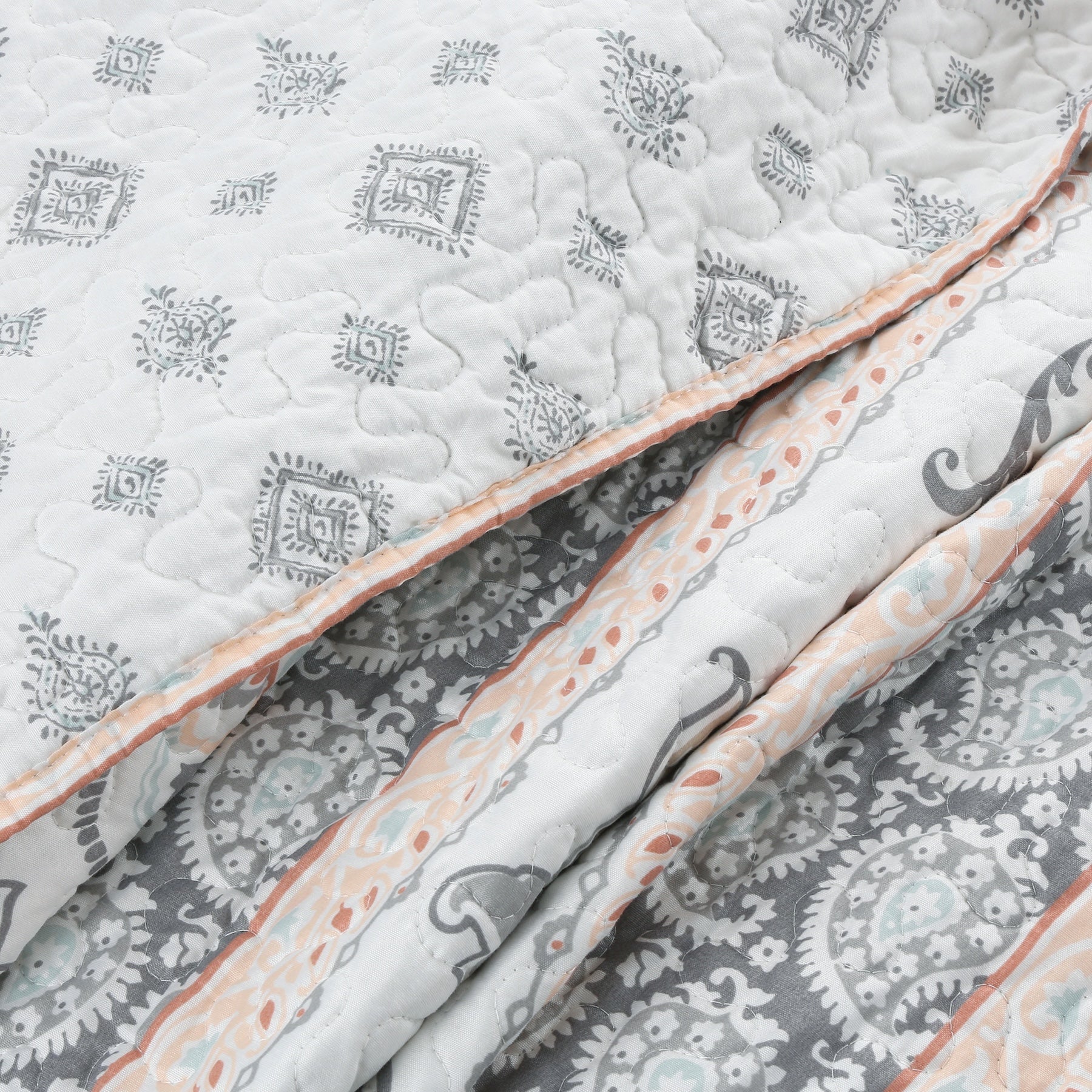 Peach paisley floral reversible quilt bedding set with aqua blue and grey accents on a farmhouse style bed.
