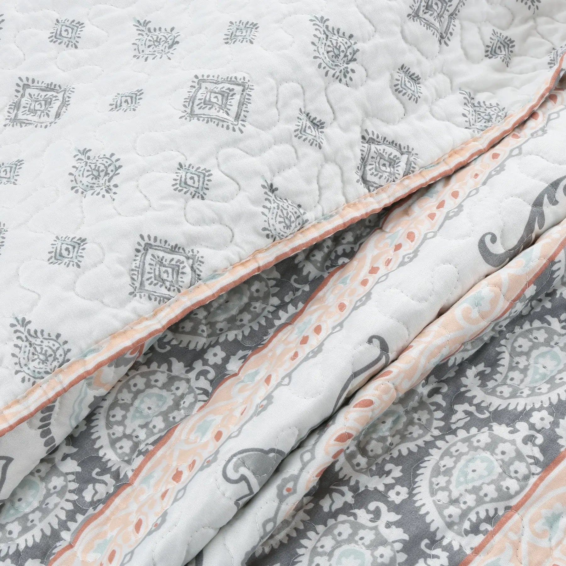 Peach paisley floral reversible quilt bedding set with aqua blue and grey accents on a farmhouse style bed.