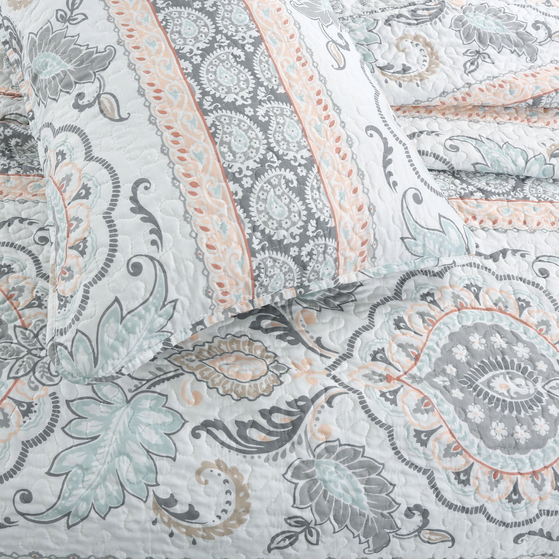 Peach paisley floral reversible quilt bedding set with aqua blue and grey accents on a farmhouse style bed.