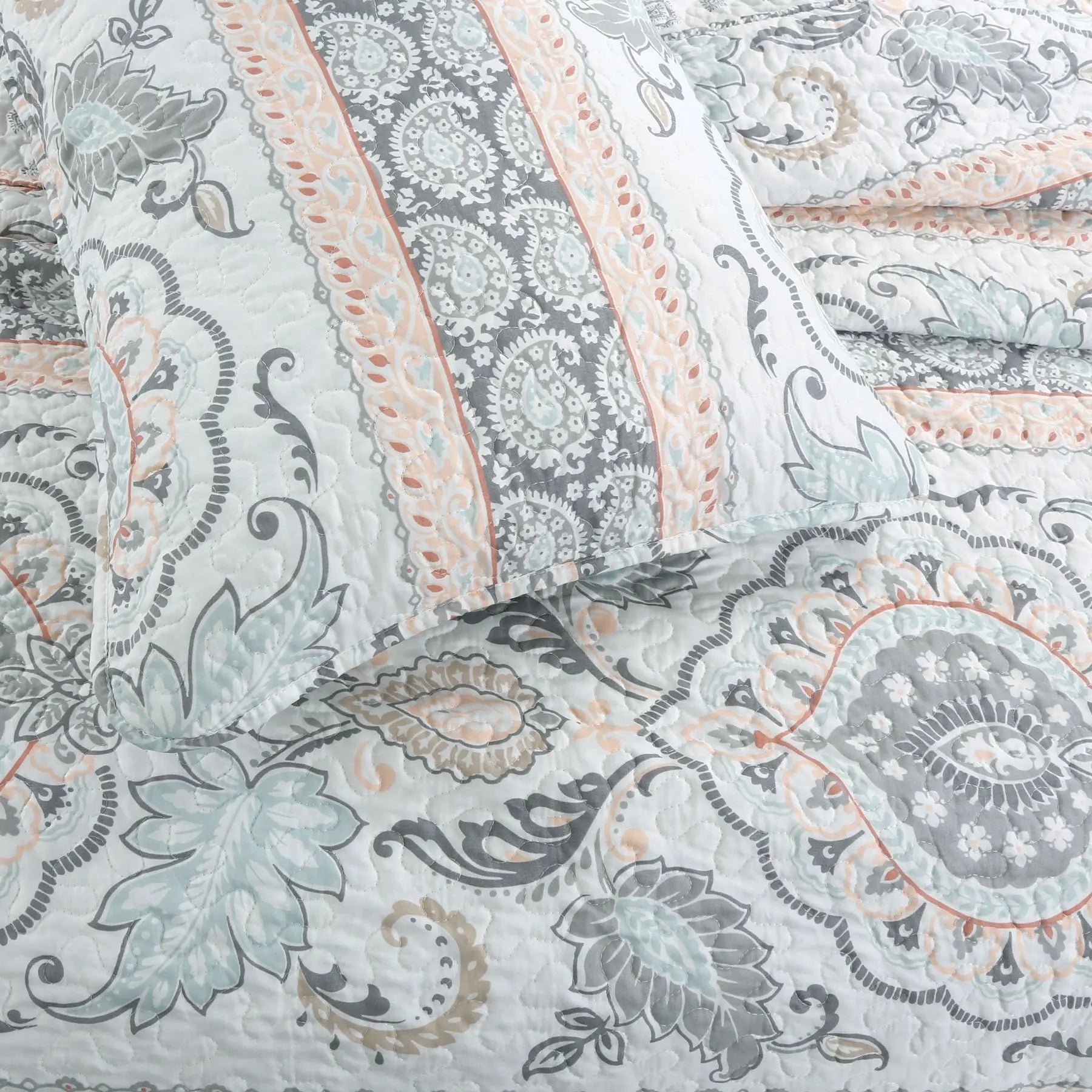 Peach paisley floral reversible quilt bedding set with aqua blue and grey accents on a farmhouse style bed.