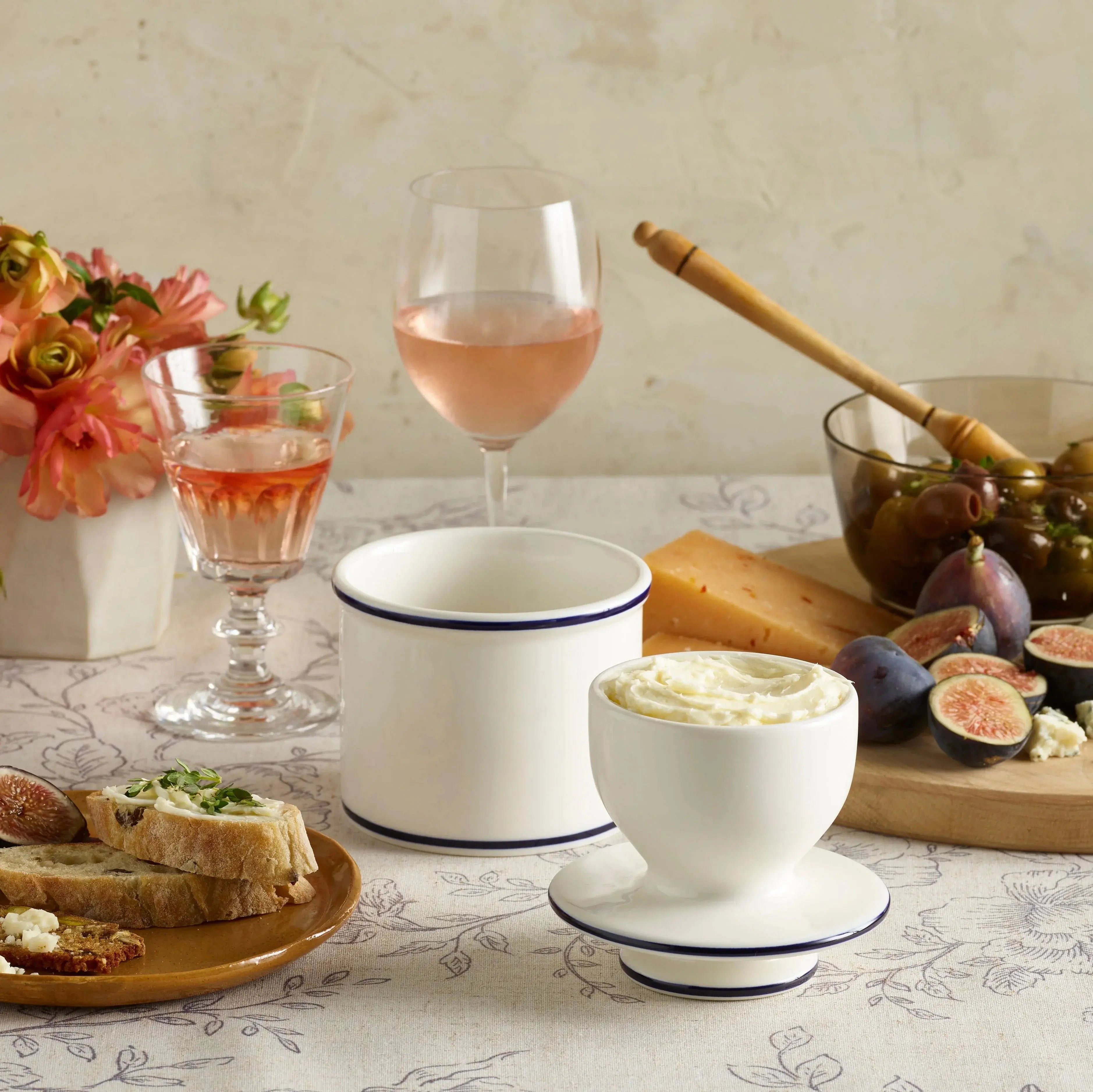 Cozy farmhouse table setting with white enamelware, figs, cheese, olives, and rosé wine for rustic home decor