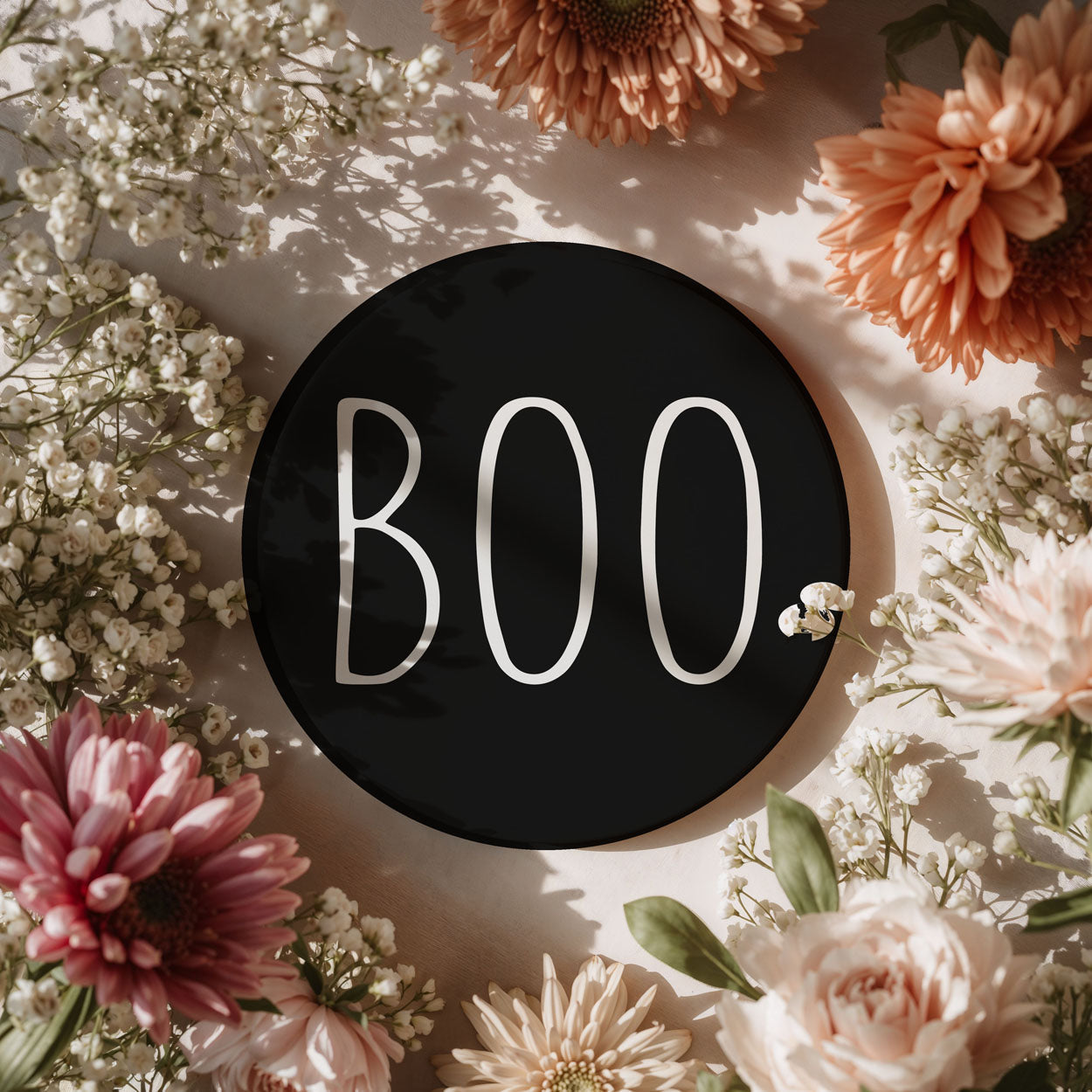 Black circle with 'BOO' text surrounded by flowers on a light background