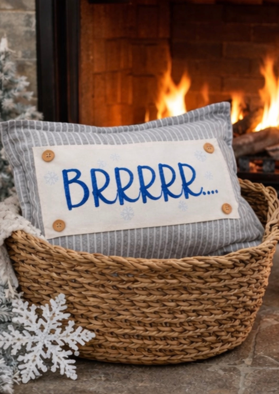 A cozy woven basket holding a gray striped pillow with a white label that reads “BRRRR.