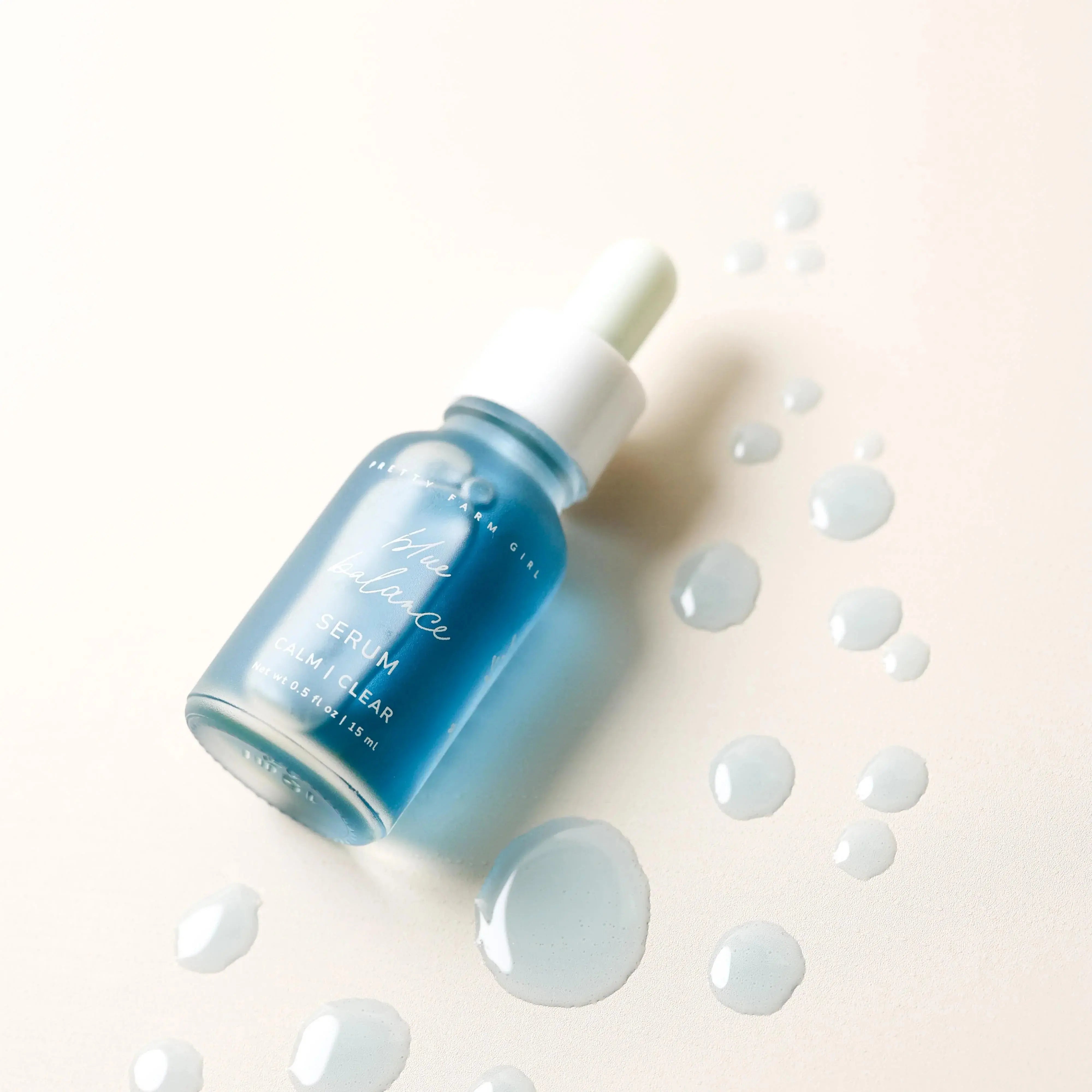 Blue Balance Serum bottle with dropper, calm clear skincare, drops on cream background