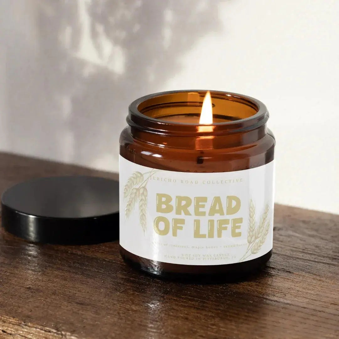 Bread of Life soy wax candle in amber jar, farmhouse cozy home decor with wheat design, lit on wood surface