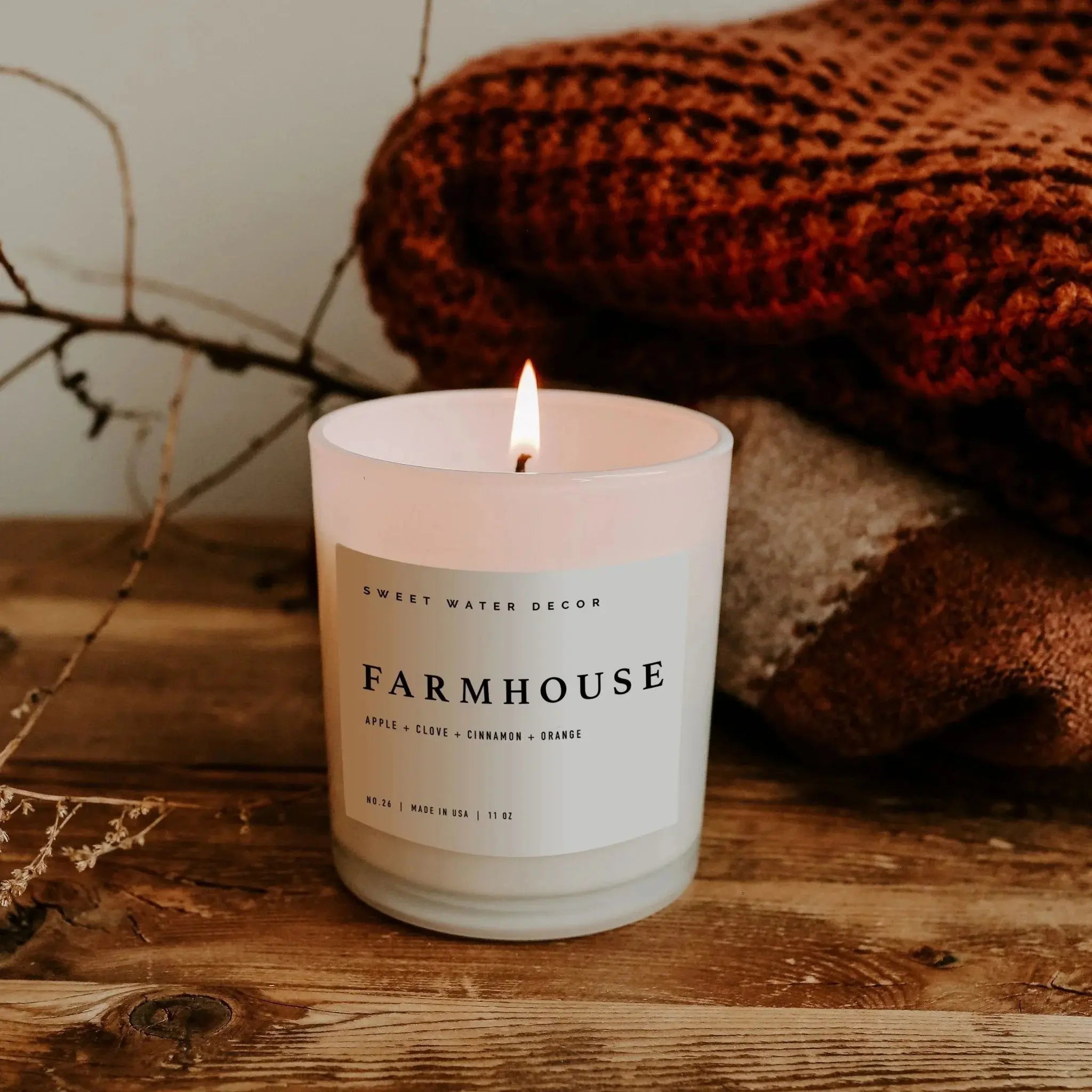 Lit Farmhouse scented candle with apple, clove, cinnamon, orange notes on rustic wood, cozy home decor