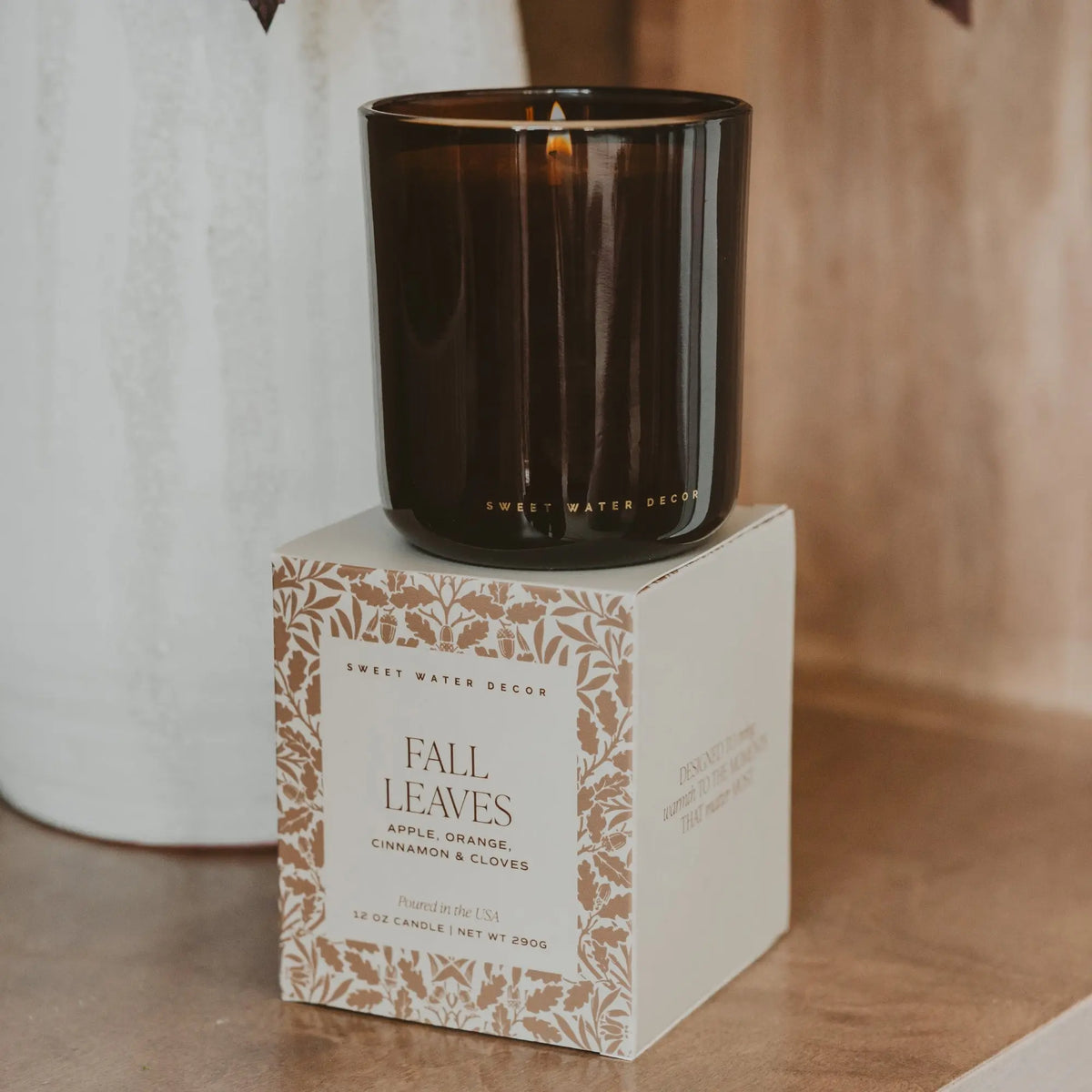 Black candle on a decorative box labeled 'Fall Leaves' with a blurred background
