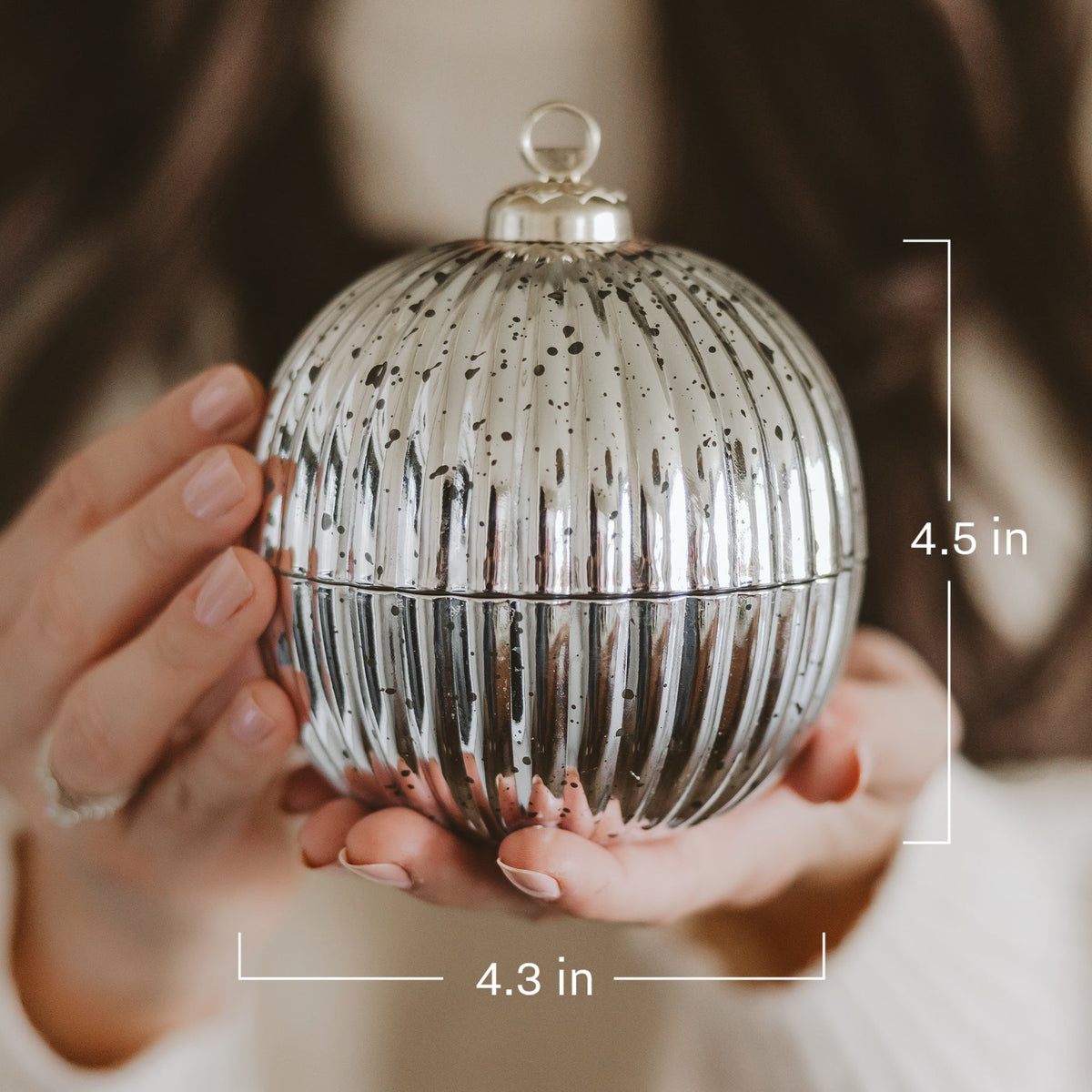 A person holds a round ribbed metallic ornament container with a silver and black speckled finish. White measurement lines and text indicate dimensions of 4.