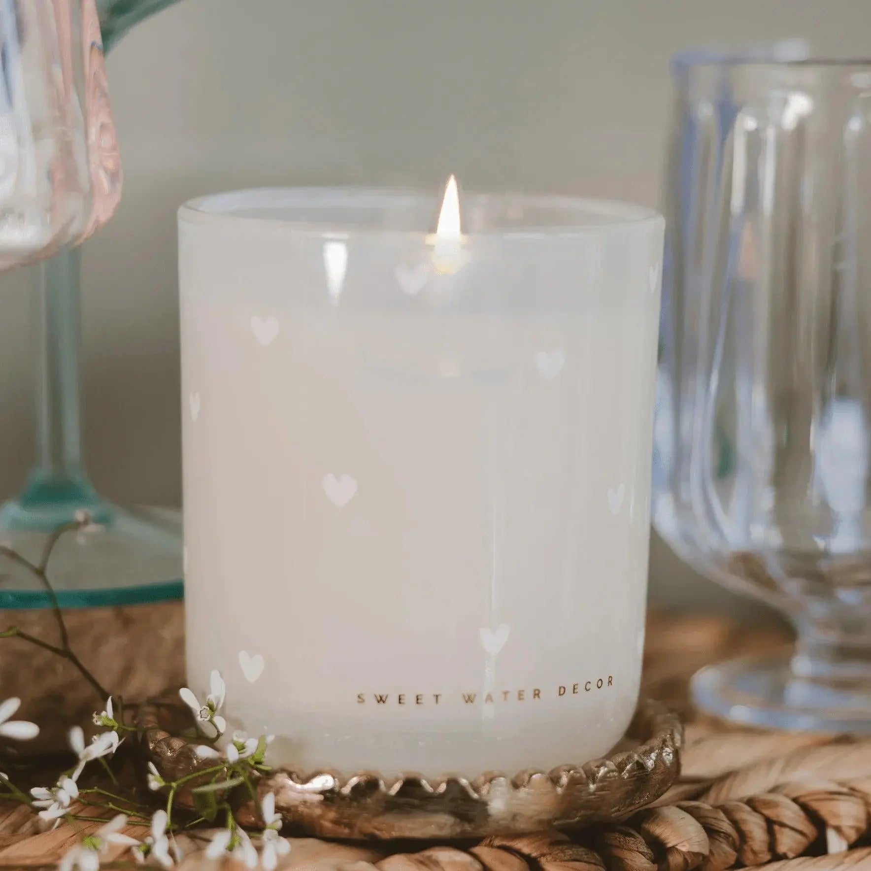 Lit white heart-patterned candle in frosted glass, cozy farmhouse decor with delicate flowers and vintage glassware