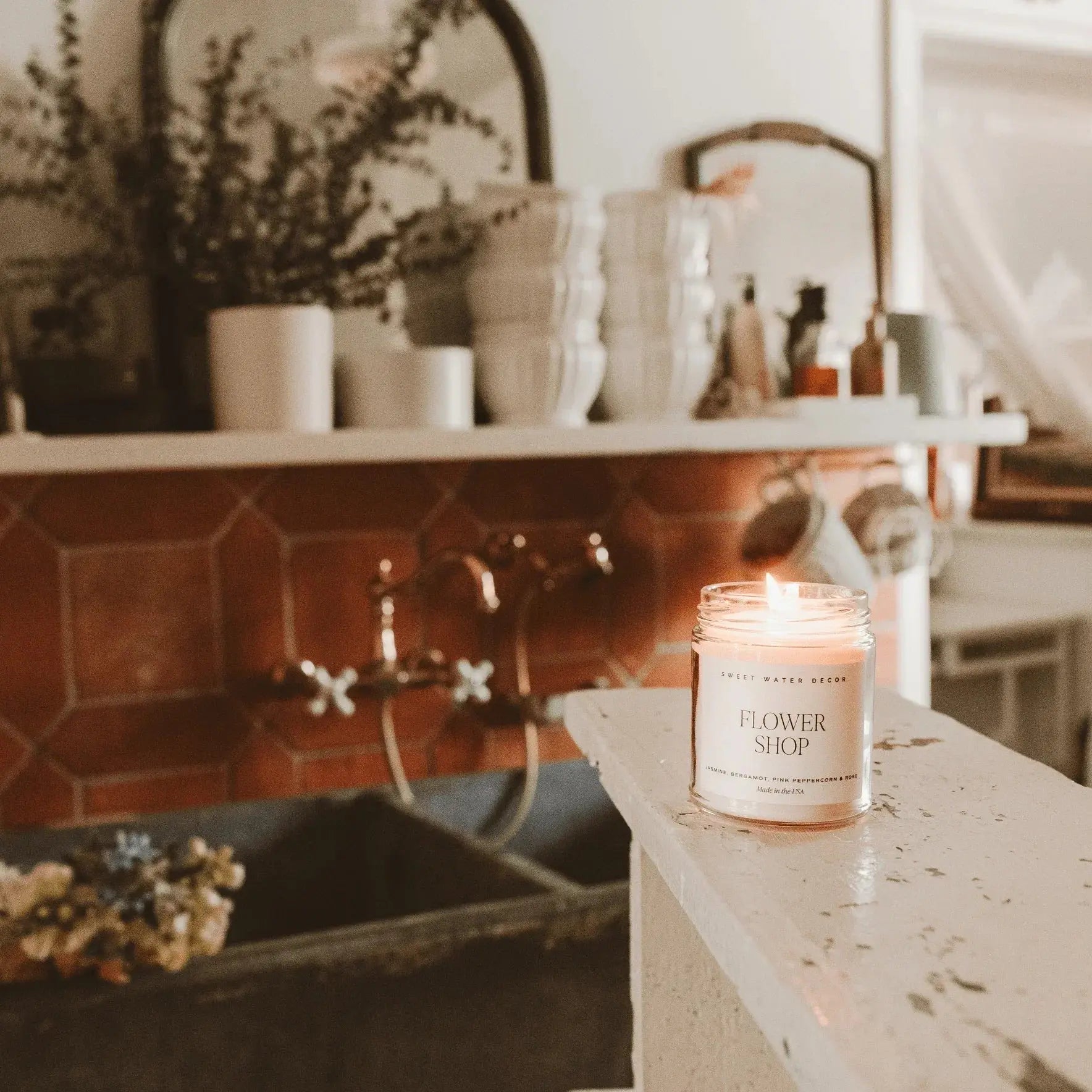 Flower Shop scented candle lit on rustic bathroom counter, cozy farmhouse decor with terracotta tiles