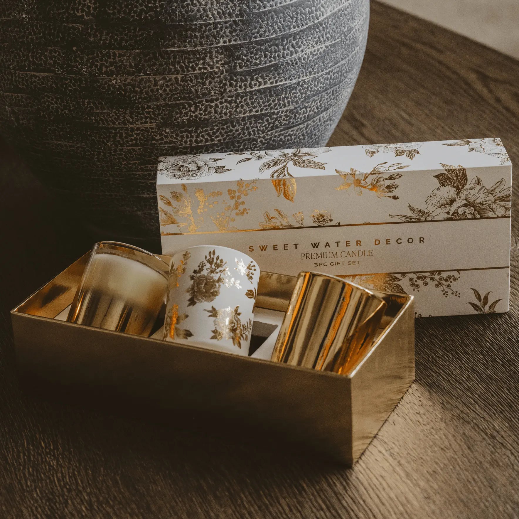 Decorative candle set with floral design packaging on a wooden surface