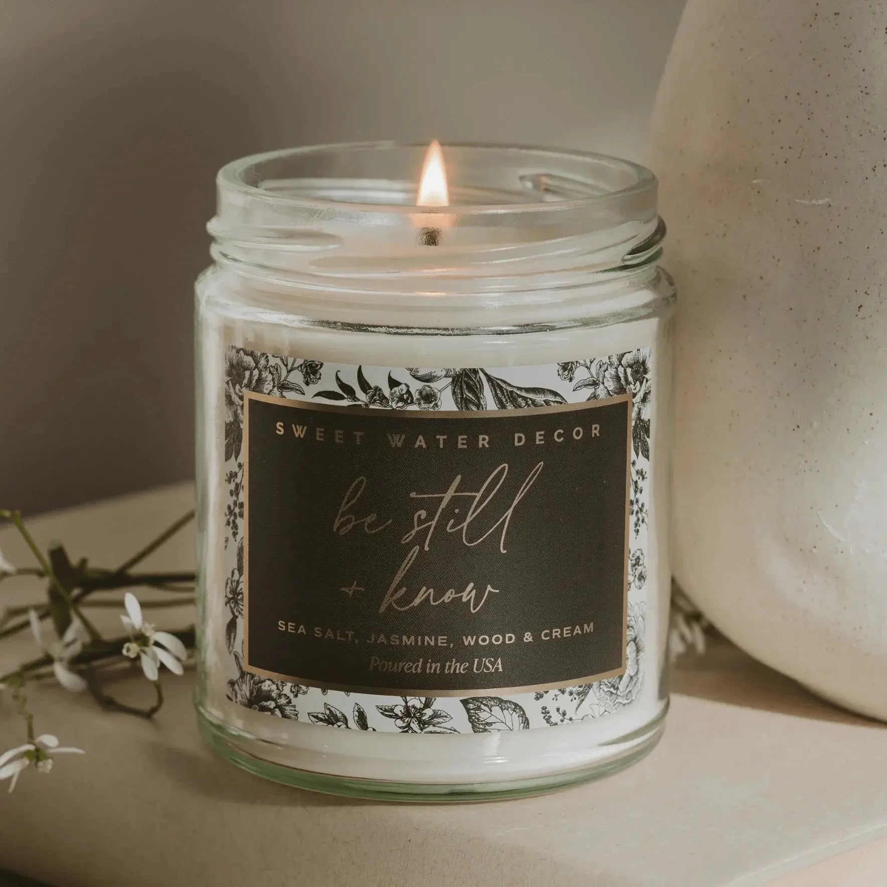 Lit 'Be Still + Know' candle with sea salt, jasmine, wood & cream scent, farmhouse decor style