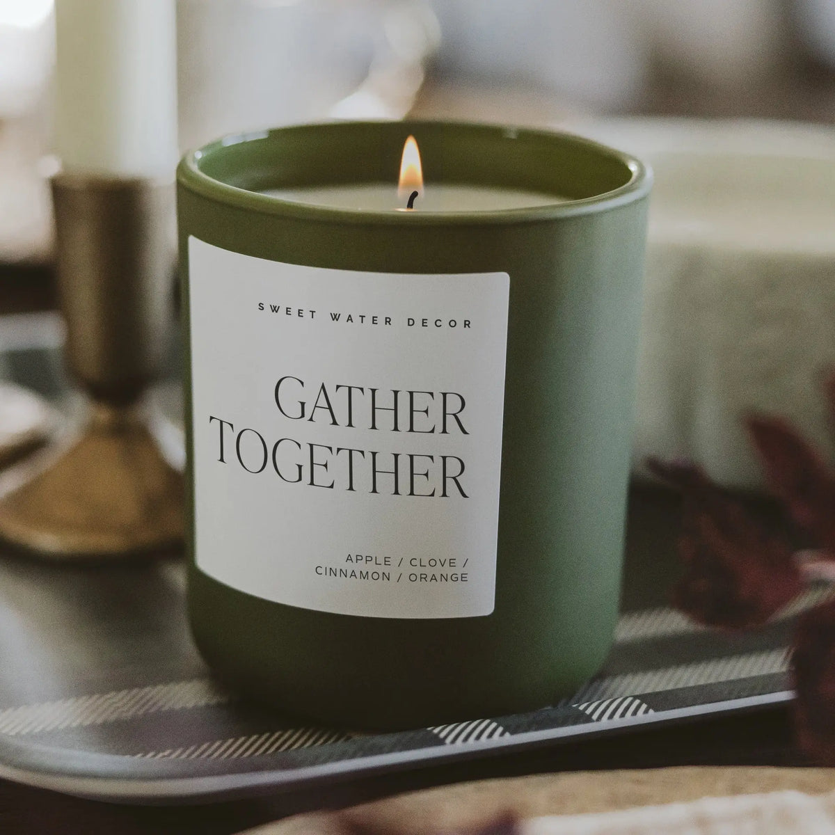 Green candle with 'Gather Together' label on a table