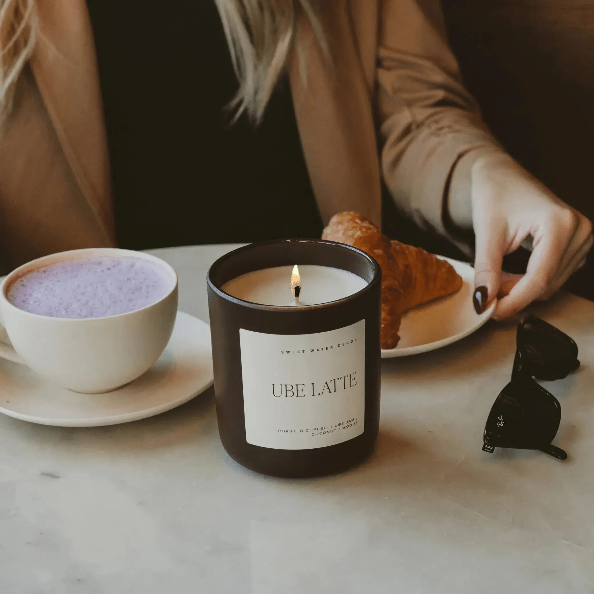 Ube Latte scented candle with purple latte and croissant on marble table, cozy home decor vibe