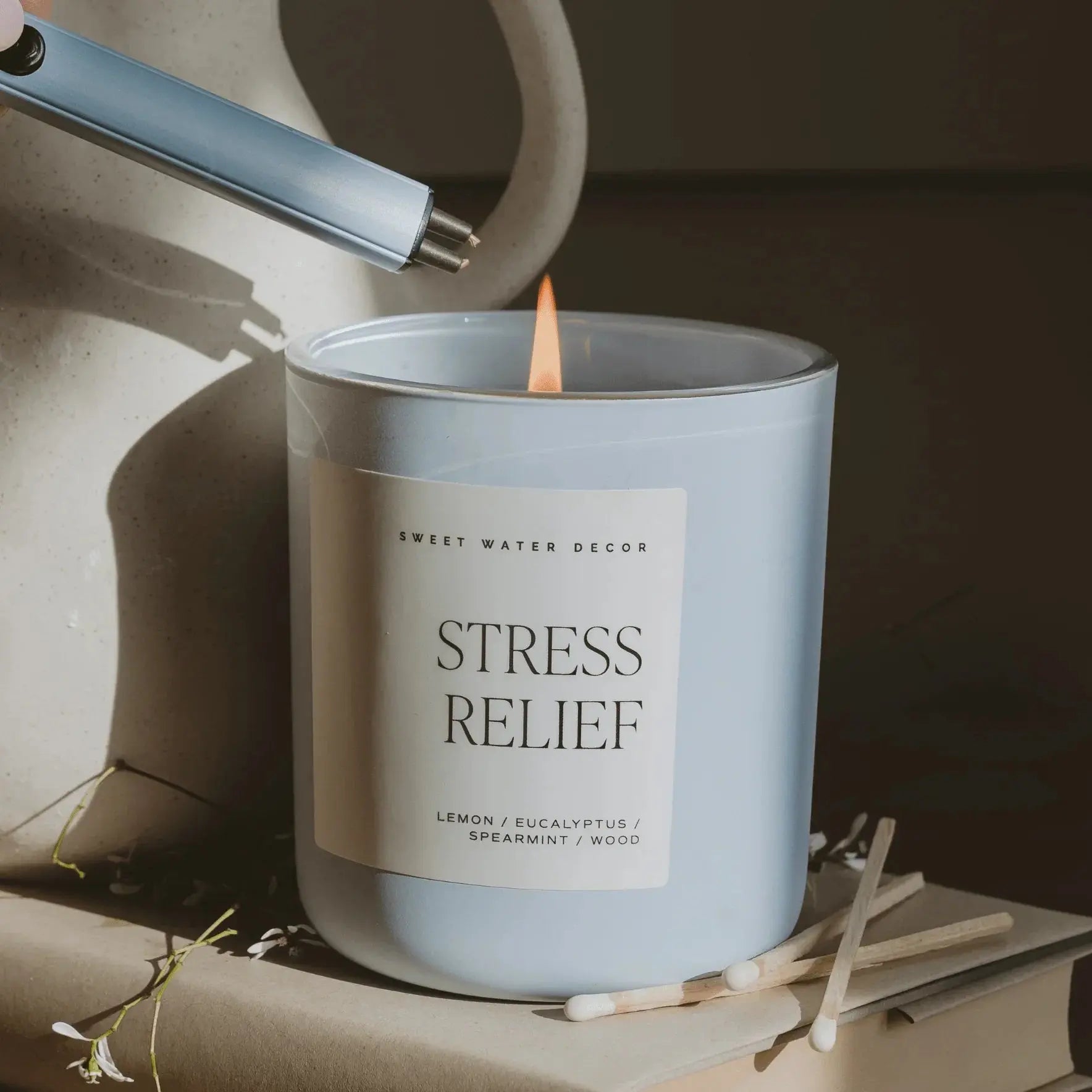 Stress Relief scented candle with lemon eucalyptus spearmint wood notes, lit with lighter, cozy home decor