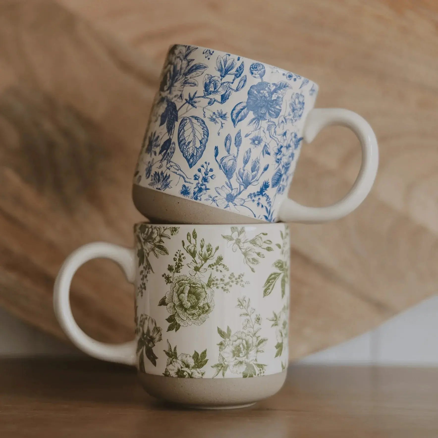 Blue and green floral ceramic mugs stacked on wooden surface, farmhouse style home decor