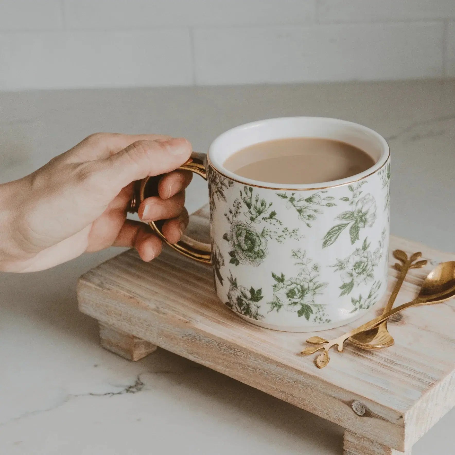 Floral coffee mug with gold handle on rustic wood tray, cozy farmhouse decor