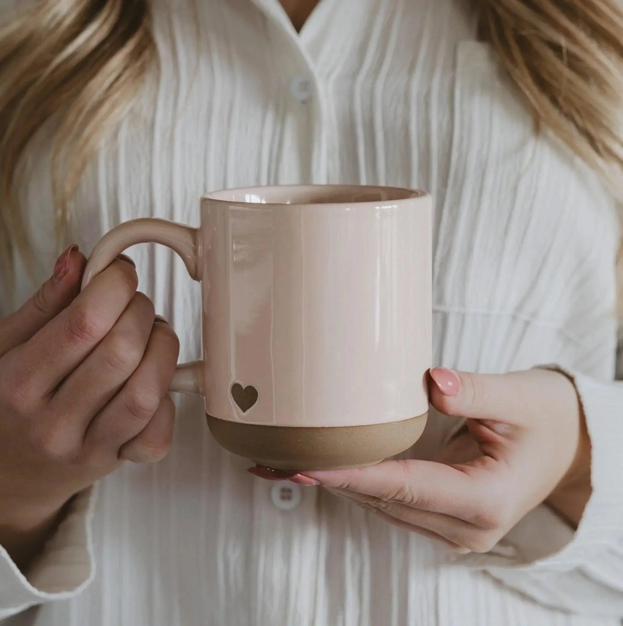 Blush ceramic mug with heart cutout, held by woman in white blouse, cozy farmhouse style