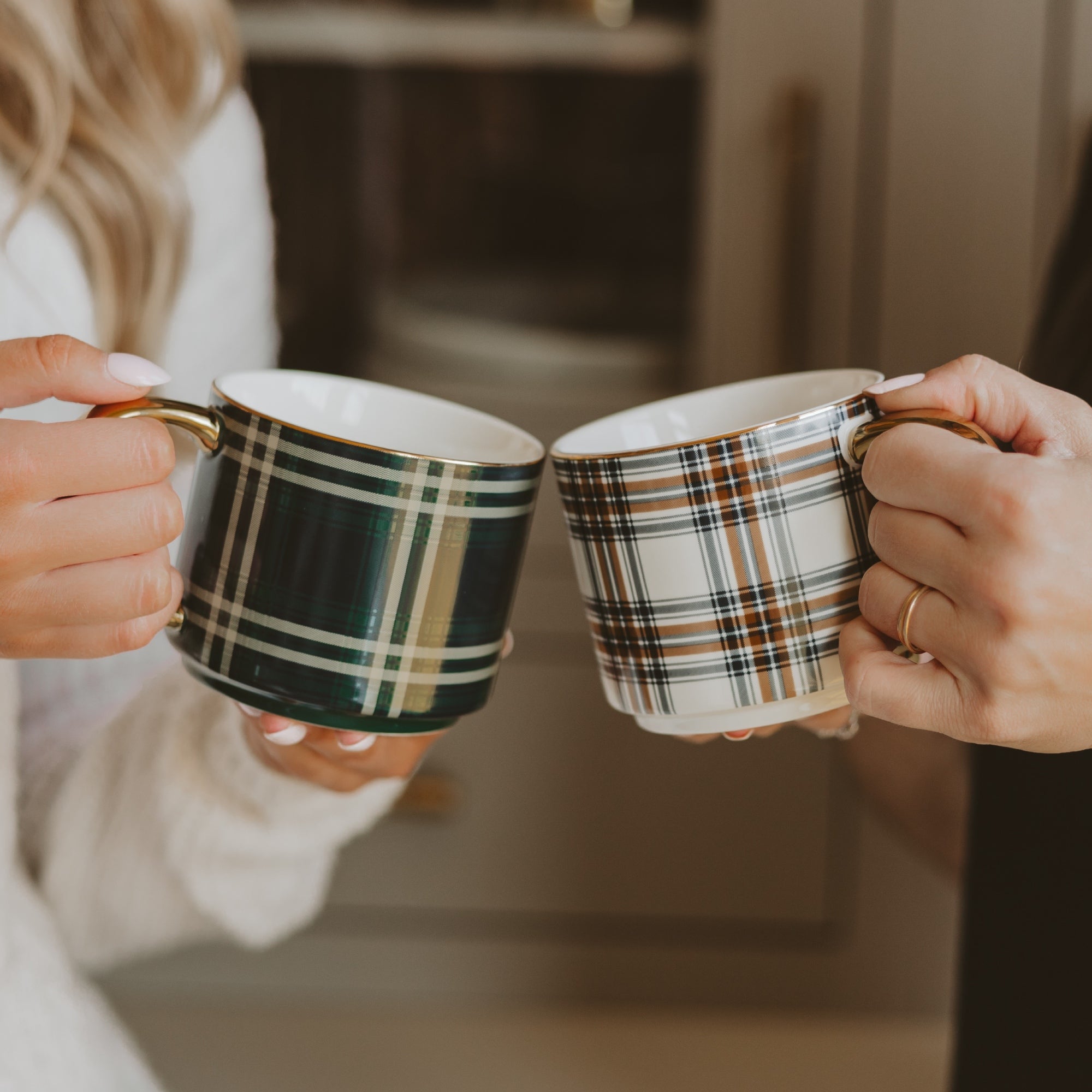 Two people holding plaid mugs in a cozy indoor setting