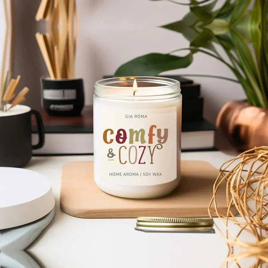 Candle labeled 'comfy & cozy' on a wooden coaster with a blurred background