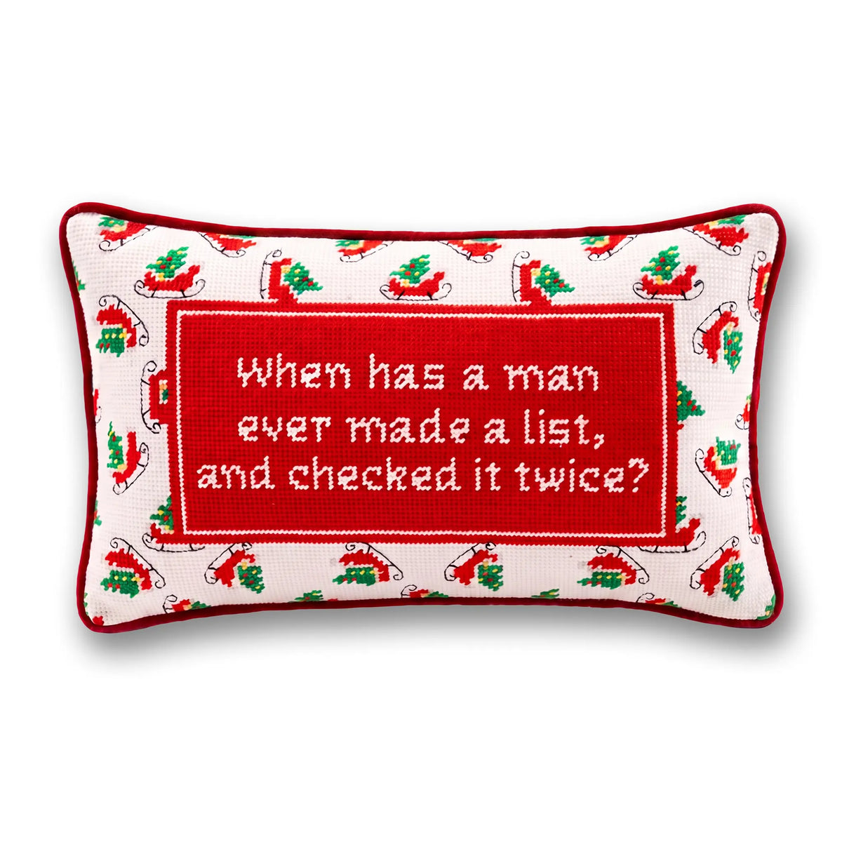 A rectangular Christmas-themed needlepoint pillow with a red border and a central red panel containing white embroidered text that reads, 'When has a man ever made a list, and checked it twice?' The surrounding border has a white background with red and green holiday motifs, including sleighs and trees.