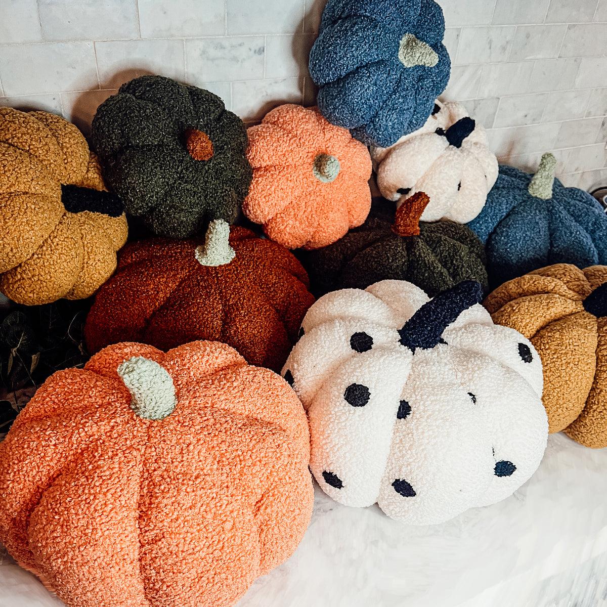 Collection of colorful plush pumpkins on a light background