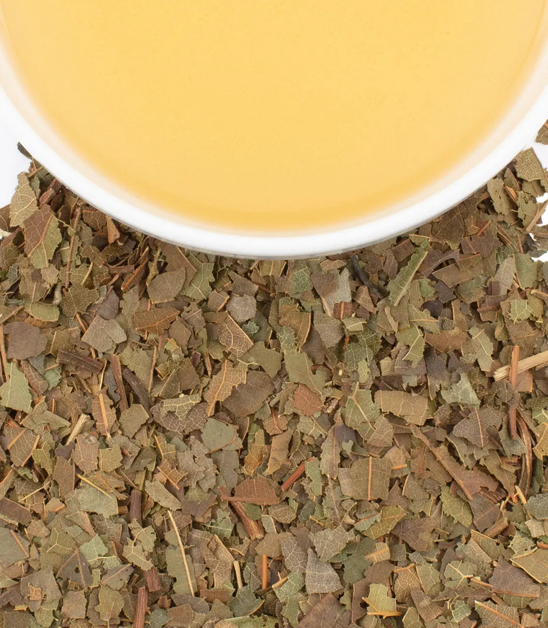 Tea leaves with a cup of tea in the background