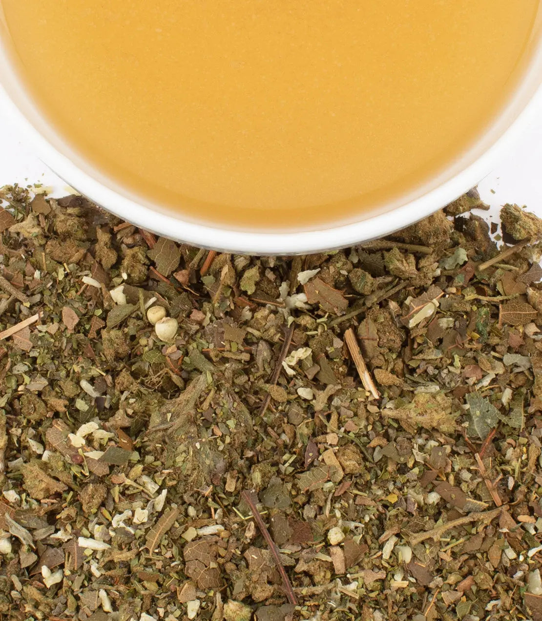 Close-up of dried herbs with a cup of tea in the background