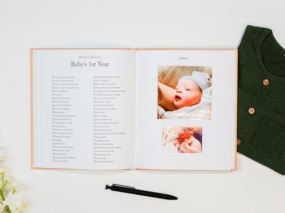Open photo album with baby milestone photos and text, next to a green knitted sweater.