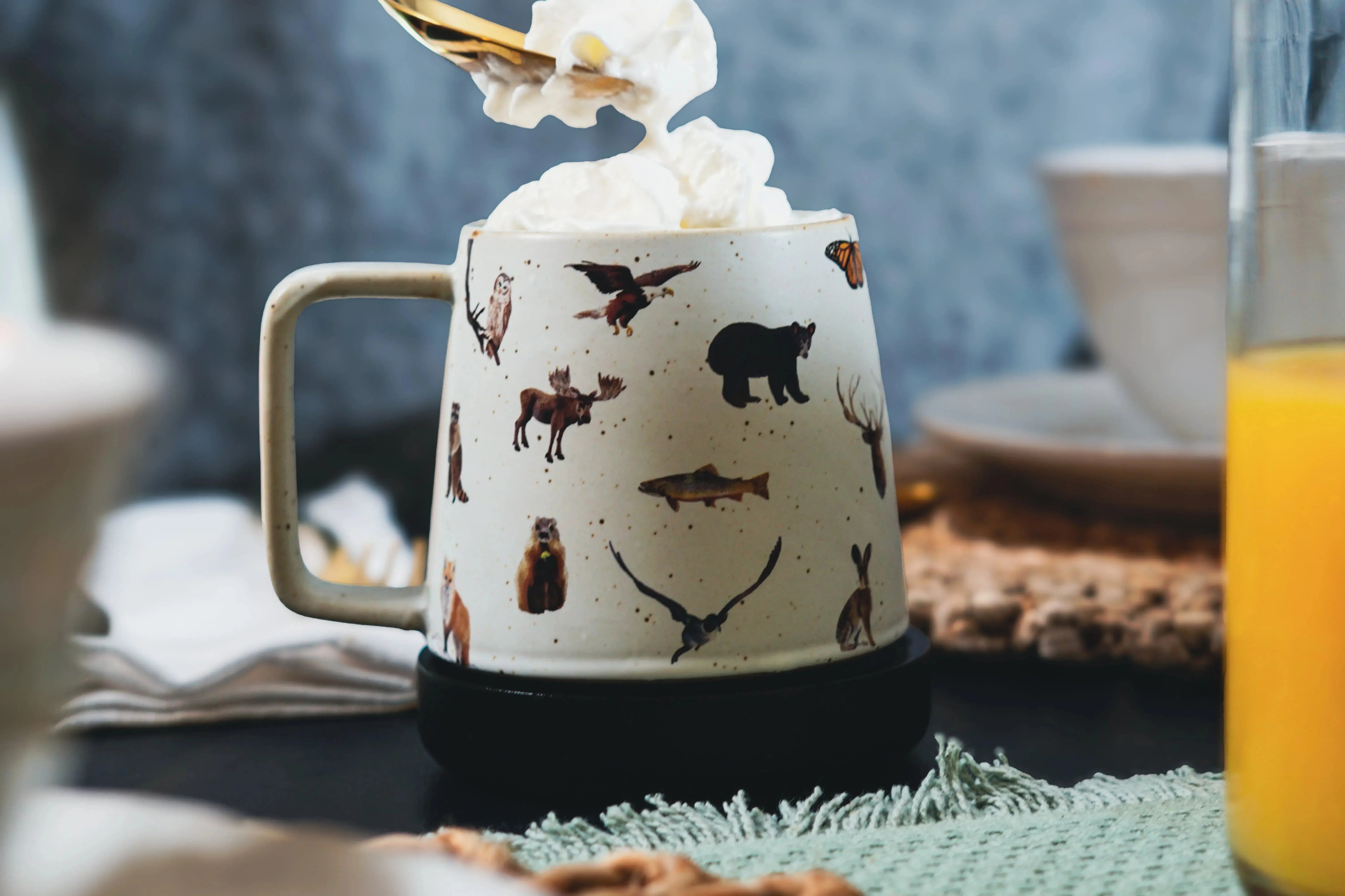 Cozy farmhouse mug with forest animals, topped with whipped cream, perfect for warm drinks and cottage style decor