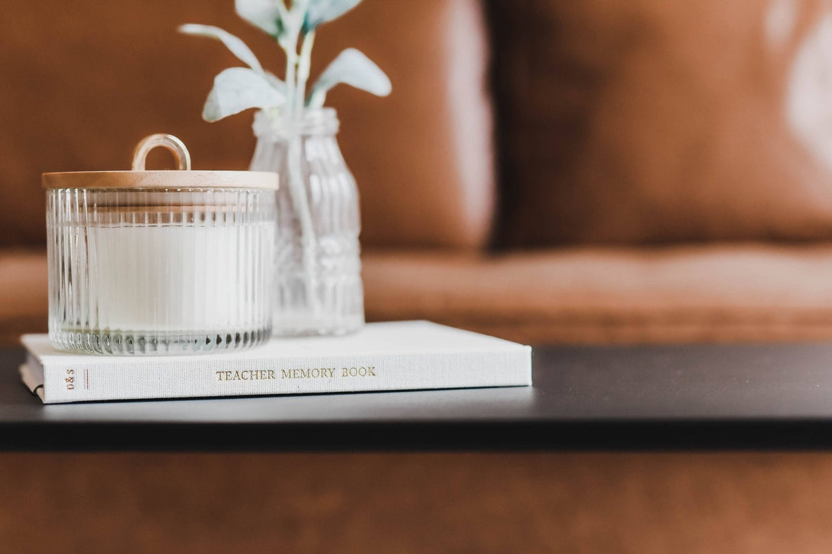 Candle, vase with flowers, and book on a table with a blurred background