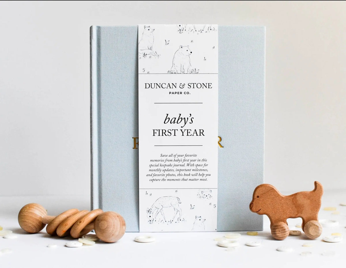 Baby's first year memory book by Duncan & Stone with wooden toys on a light background