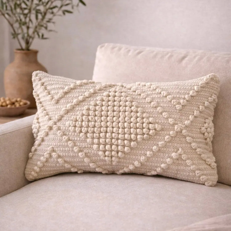 Cream textured knit pillow with pom-pom pattern on cozy sofa, farmhouse decor accent