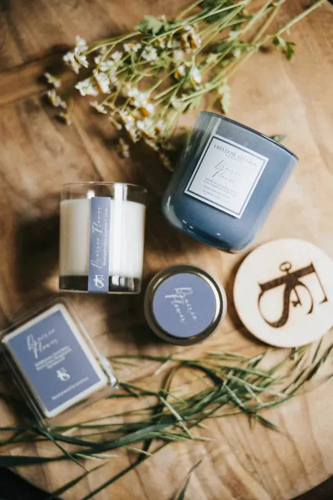 Cozy farmhouse candle set with dried flowers, wooden coaster, and bath essentials on rustic wood