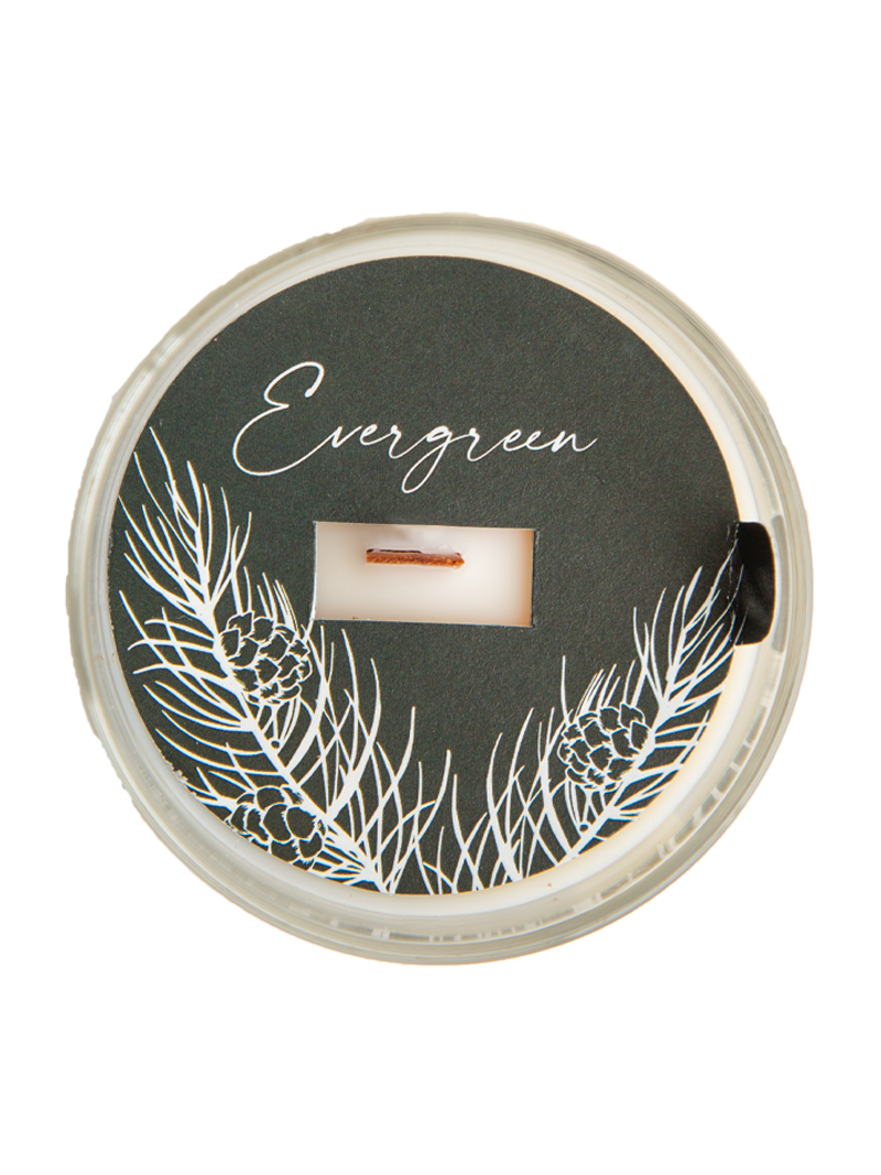 Candle in a container with 'Evergreen' text and winter-themed design on a white background